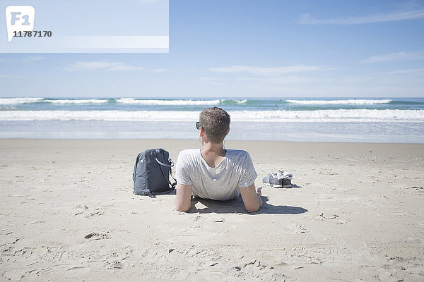 Rückansicht des Mannes mit Rucksack am Strand bei Sonnenschein