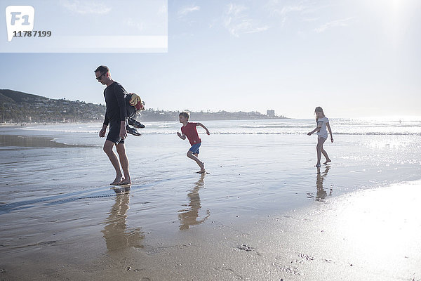 Väterchen in voller Länge mit Kindern  die an einem sonnigen Tag Urlaub am Strand machen