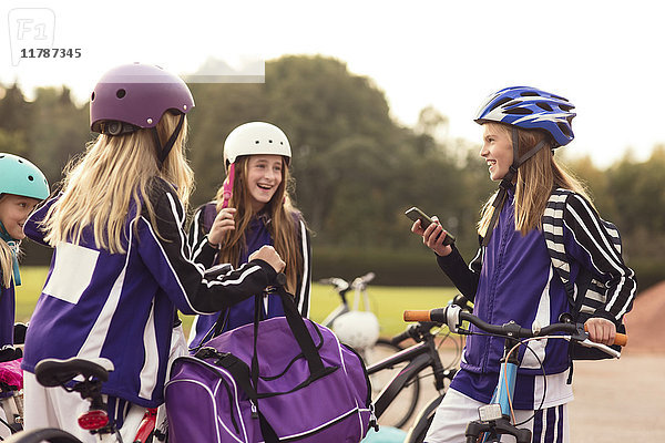 Glückliche Mädchen mit Helm stehend mit Fahrrädern gegen den Himmel