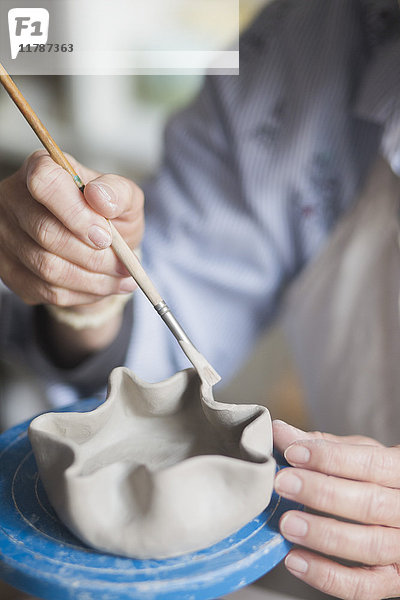 Mittelteil der älteren Töpferin mit Pinsel auf Vase in der Werkstatt