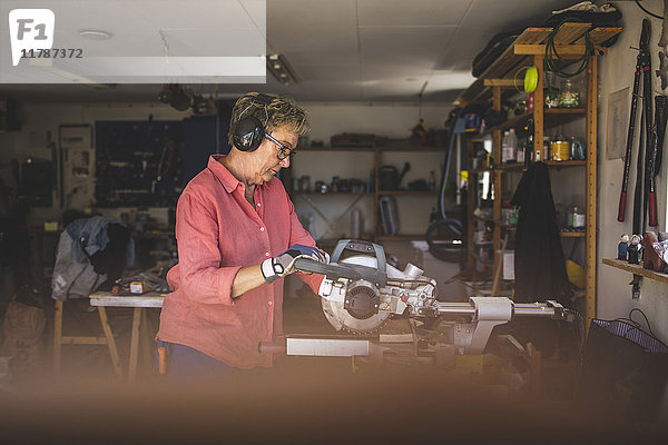 Seniorin mit Kreissäge in der Werkstatt