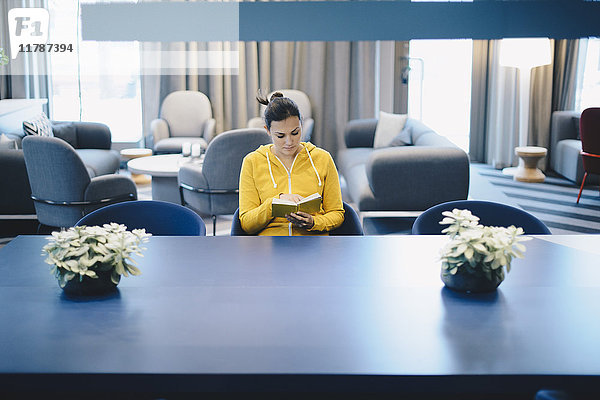 Mittlere erwachsene Geschäftsfrau liest Buch in der Bürolobby