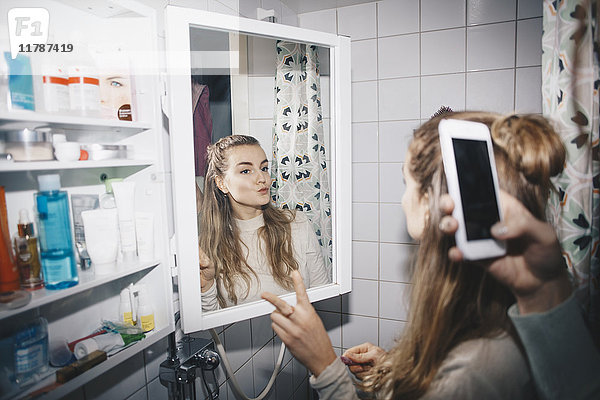 Abgeschnittene Hand einer Frau  die eine Freundin in Spiegelreflexion im Schlafsaal fotografiert.