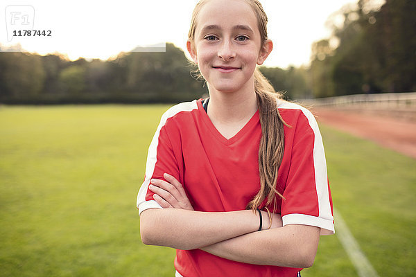 Porträt eines glücklichen Mädchens mit gekreuzten Armen auf dem Fußballfeld
