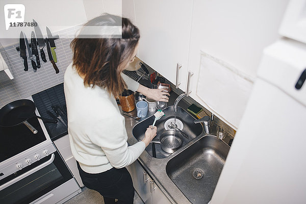 Hochwinkelansicht der Frau beim Geschirrspülen in der Küche im Wohnheim