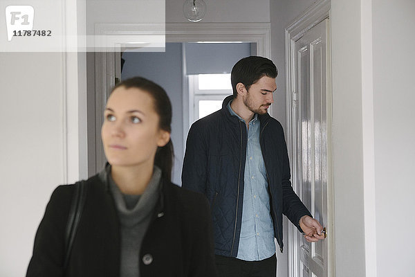 Junger Mann schaut auf die Tür  während er mit einer Frau im Flur steht.