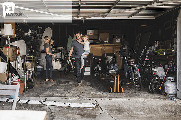 Mittlere erwachsene Eltern mit Kindern bei der Arbeit im Abstellraum in der Garage