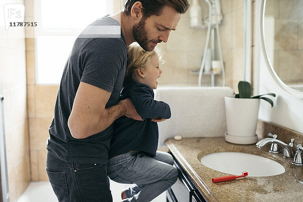 Seitenansicht des Vaters mit Tochter am Waschbecken im Bad