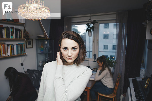 Porträt einer jungen Frau mit Freundinnen im Studentenwohnheimzimmer