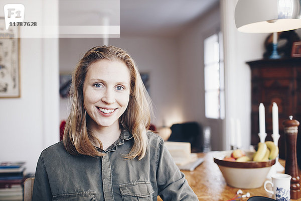 Porträt einer jungen Frau  die zu Hause am Tisch sitzt