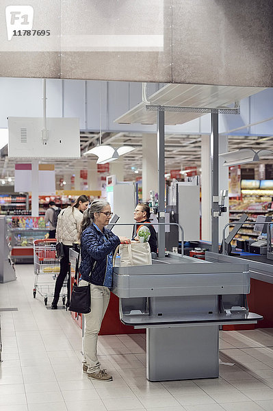 Frau mit Einkaufstasche an der Kasse im Supermarkt
