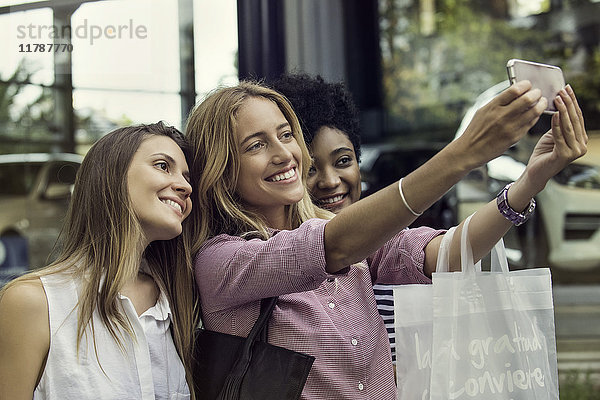 Freunde  die ein Smartphone benutzen  um einen Selfie beim Einkaufen mitzunehmen.