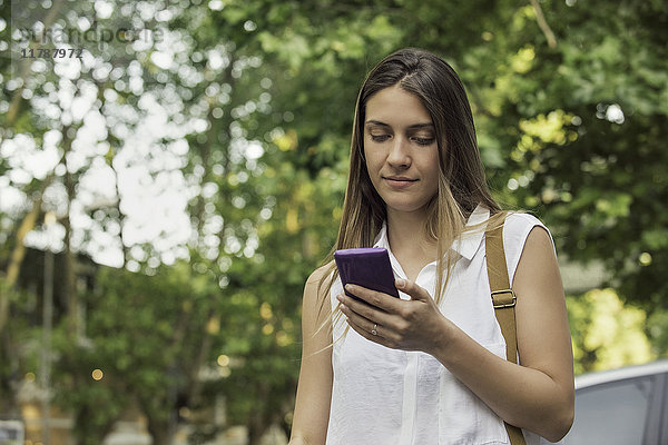 Junge Frau überprüft Smartphone im Freien