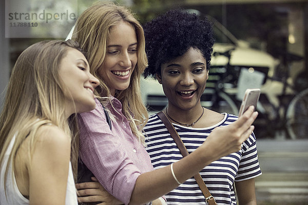 Freunde  die ein Smartphone benutzen  um einen Selfie zu nehmen.