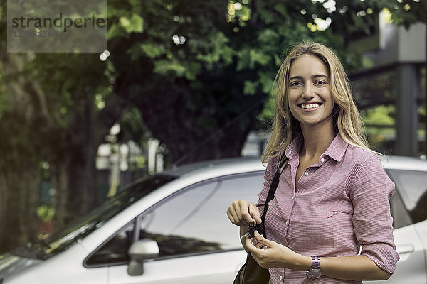 Junge Frau hält Autoschlüssel  lächelt fröhlich