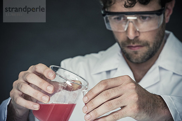 Wissenschaftler gießt Flüssigkeit in das Reagenzglas im Labor
