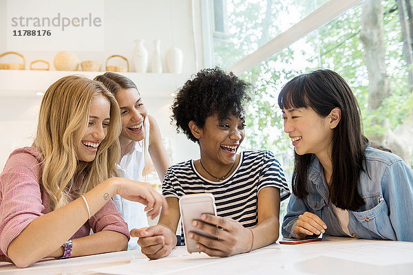 Junge Frauen  die Smartphones anschauen und gemeinsam lachen