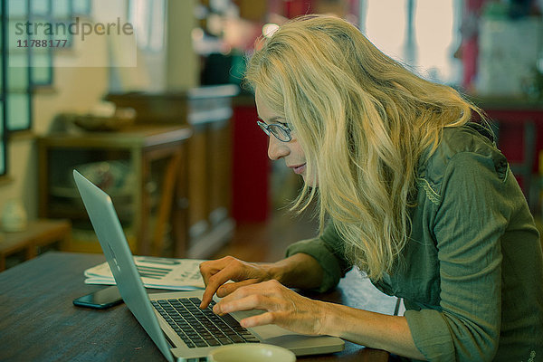 Reife Frau mit Laptop zu Hause