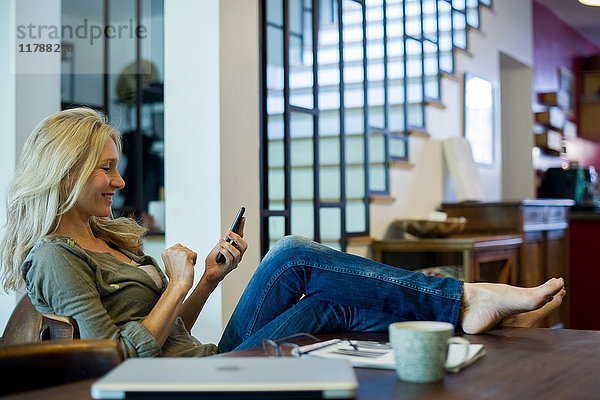 Frau entspannt zu Hause mit Smartphone