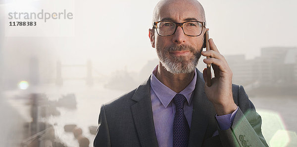 Porträt eines seriösen Geschäftsmannes am Handy auf der urbanen Brücke  London  UK