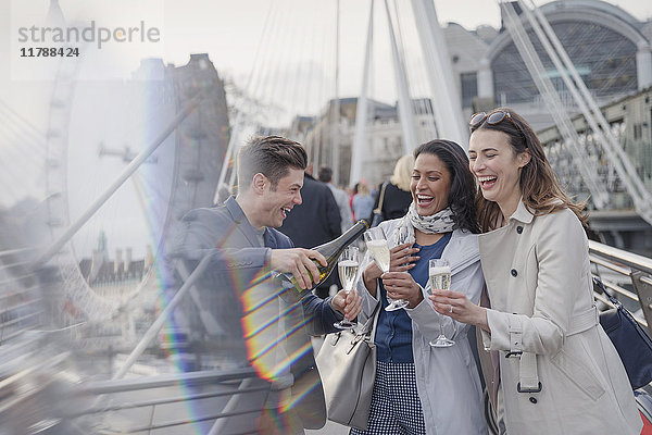 Lächelnde  glückliche Freunde beim Feiern  Champagner gießen in der Stadt  London  UK