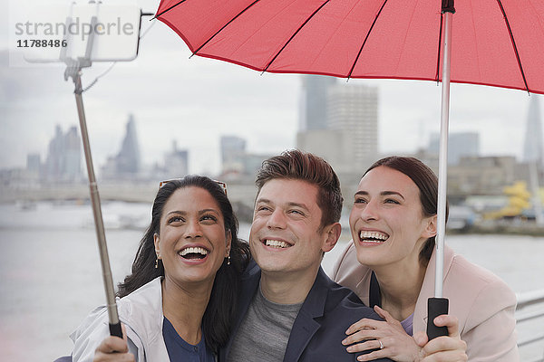 Lächelnde Freund-Touristen mit Regenschirm und Selfie-Stick  London  UK