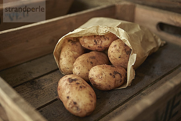 Stilleben hautnah  rustikal frisch  biologisch  gesund  schmutzige Kartoffeln im Sack in Holzkiste