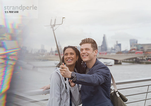 Paar Touristen  die Selfie mit Fotohandy Selfie Stick an der Themse River Waterfront  London  UK nehmen.