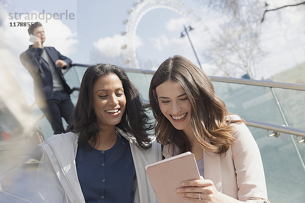 Lächelnde Geschäftsfrauen mit digitalem Tablett im Freien