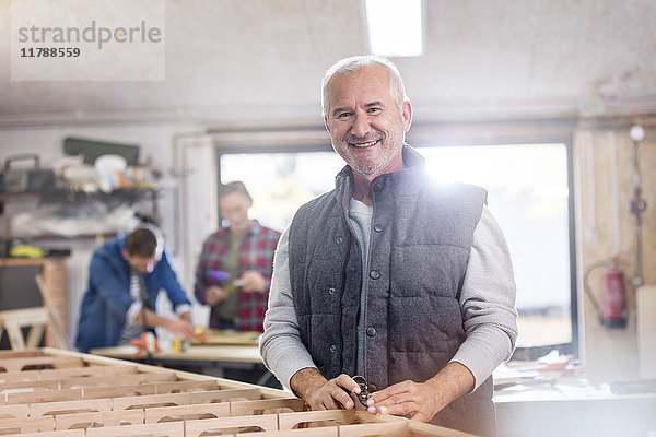 Portrait lächelnder Schreiner bei der Arbeit auf dem Holzboot in der Werkstatt