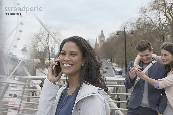 Lächelnde Frau beim Telefonieren auf der urbanen Brücke  London  UK