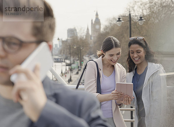 Weibliche Freunde mit digitalem Tablett auf urbaner Brücke  London  UK