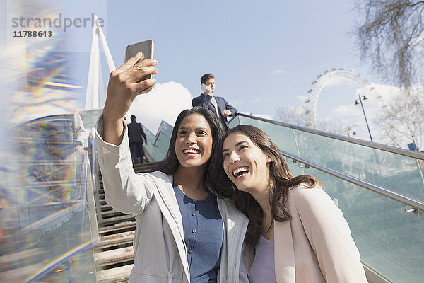 Enthusiastische  lächelnde Frauen-Freunde  die Selfie mit Fotohandy auf einer sonnigen  urbanen Treppe nehmen  London  UK