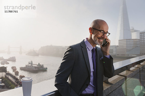 Geschäftsmann im Gespräch auf dem Handy auf der sonnigen  städtischen Brücke  London  UK