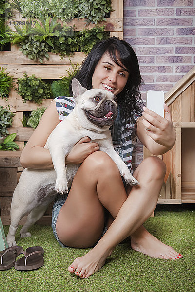 Frau und französische Bulldogge mit einem Selfie auf der Terrasse