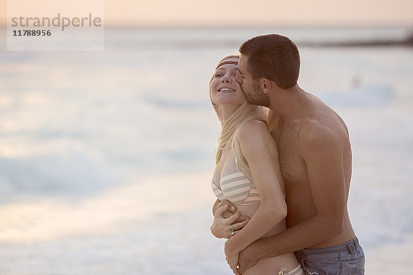 Romantisches Paar beim Küssen am Strand