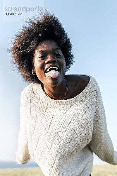 Porträt einer jungen Frau  die ihre Zunge herausstreckt.