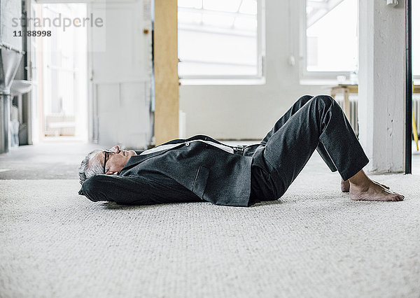 Senior Geschäftsmann auf dem Boden liegend