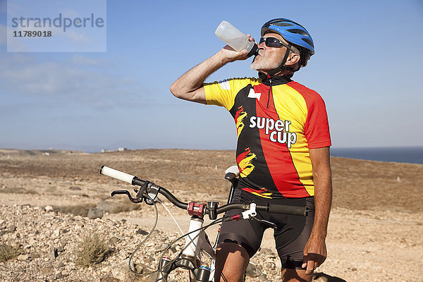 Spanien  Kanarische Inseln  Fuerteventura  Senioren mit Mountainbike aus der Flasche trinkend