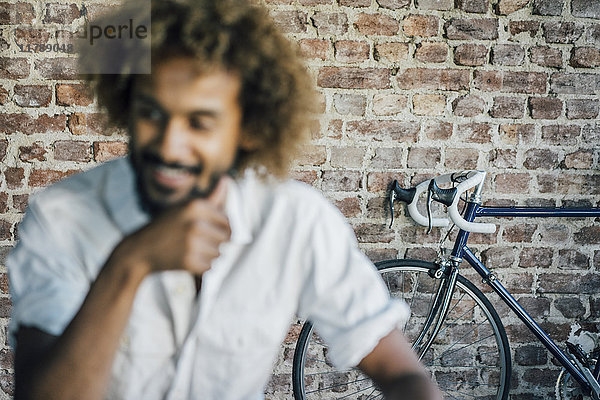 Lächelnder junger Mann mit Fahrrad im Hintergrund