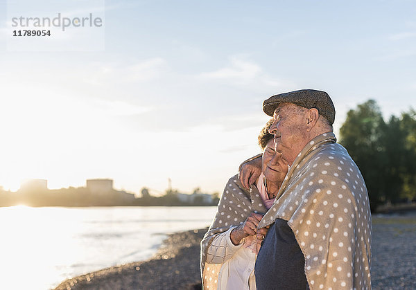 Seniorenpaar entspannt am Strand bei Sonnenuntergang