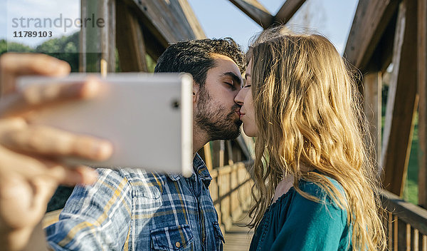 Verliebtes Paar nimmt Selfie mit Smartphone während des Kusses