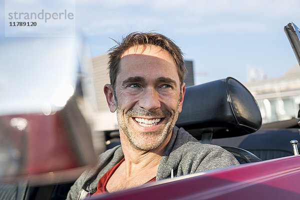 Porträt eines lächelnden reifen Mannes in seinem Sportwagen