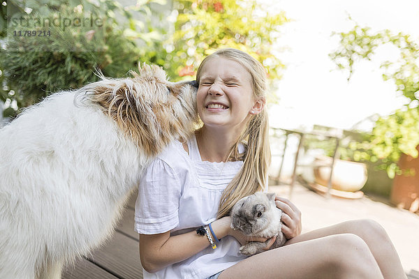 Glückliches Mädchen mit Hase und Hund im Freien