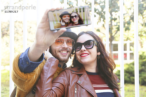 Glückliches junges Paar nimmt Selfie mit Smartphone