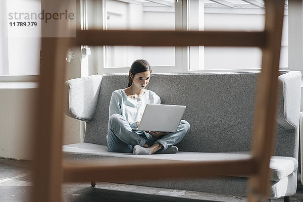 Yung Frau sitzend in ihrer neuen Wohnung mit einem Laptop