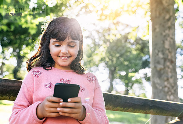 Lächelndes Mädchen sendet Nachrichten mit ihrem Smartphone