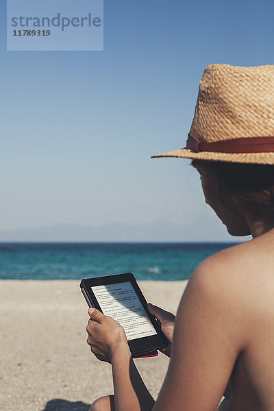 Griechenland  junge Frau am Strand liest E-Book