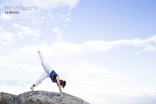 Frau bei einer Yoga-Übung auf einem Felsen