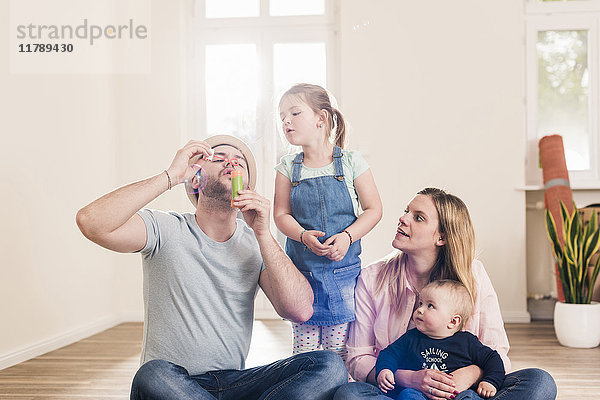 Familie bläst Seifenblasen im neuen Zuhause